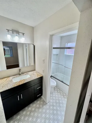 a bathroom with a granite countertop sink toilet and shower