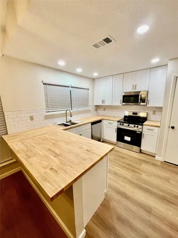 a kitchen with kitchen island a counter top space cabinets and stainless steel appliances