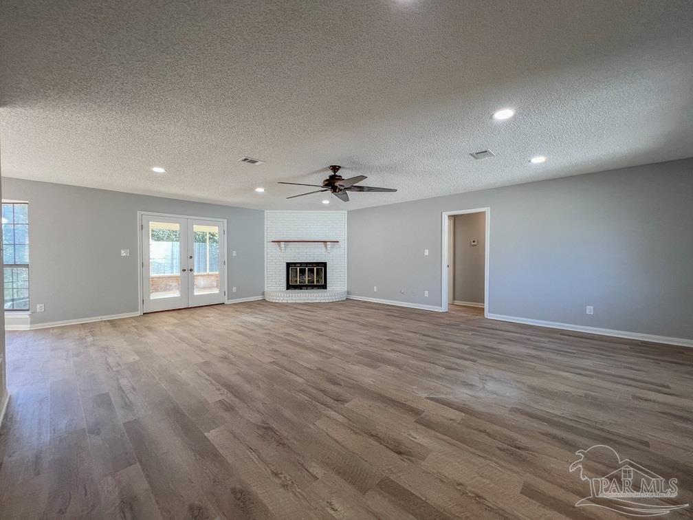 4285 Dana Street Pace, FL 32571 - Photo 20 of 26 an empty room with wooden floor fireplace and windows