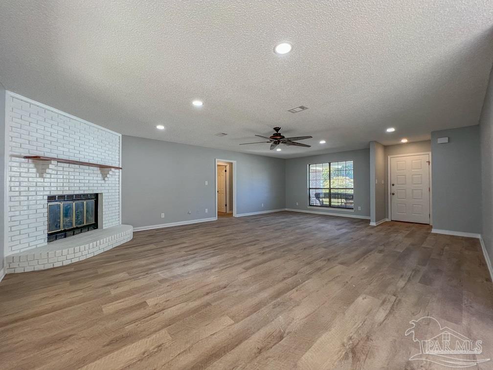 4285 Dana Street Pace, FL 32571 - Photo 2 of 26 an empty room with wooden floor fireplace and windows