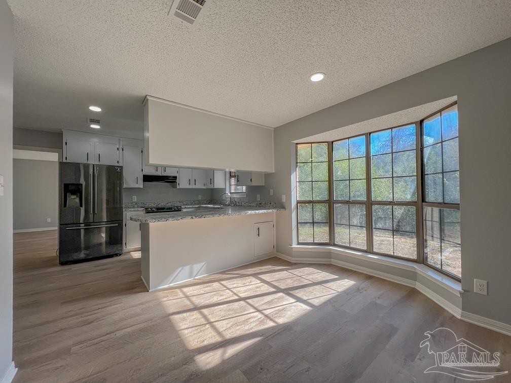 4285 Dana Street Pace, FL 32571 - Photo 4 of 26 a kitchen with stainless steel appliances kitchen island granite countertop a refrigerator a sink a stove and white cabinets with wooden floor
