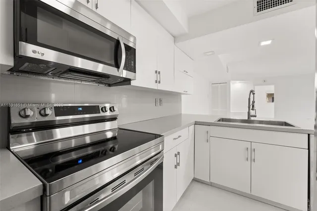 a kitchen with stainless steel appliances white cabinets and a stove top oven