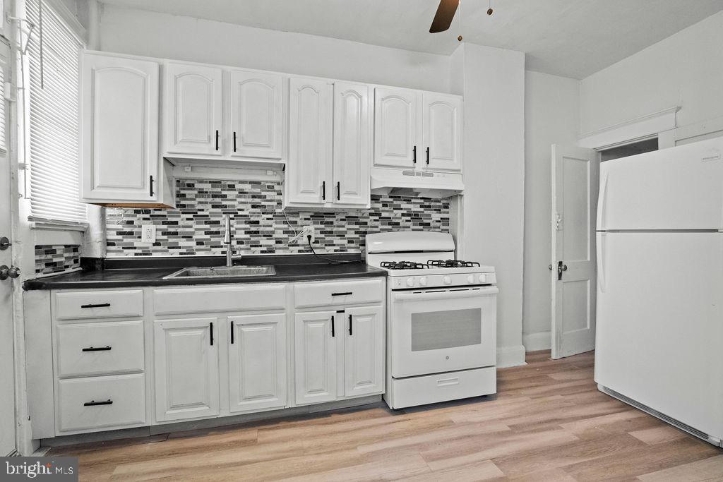 2424 West Lafayette Avenue Baltimore, MD 21216 - Photo 9 of 19 a kitchen with white cabinets and white appliances