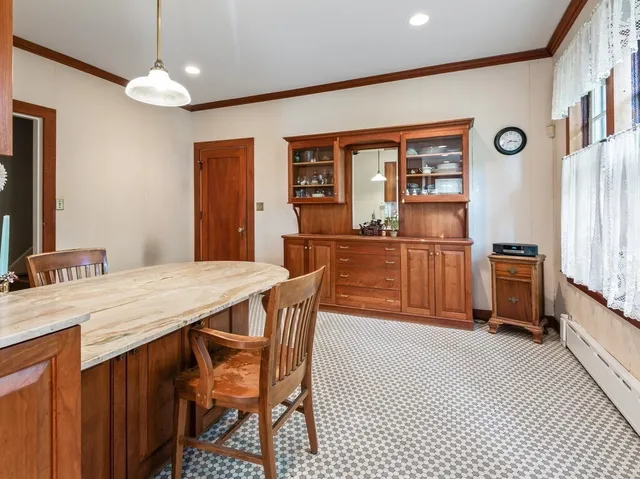 a kitchen with stainless steel appliances kitchen island granite countertop a refrigerator a stove top oven and a dining table with wooden floor