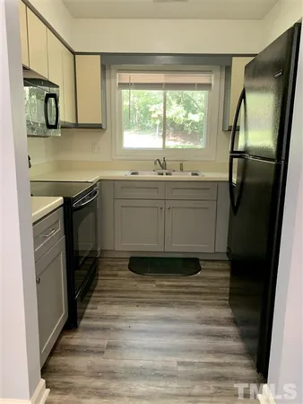 a kitchen with stainless steel appliances granite countertop a refrigerator a sink dishwasher a stove and white countertops with wooden floor