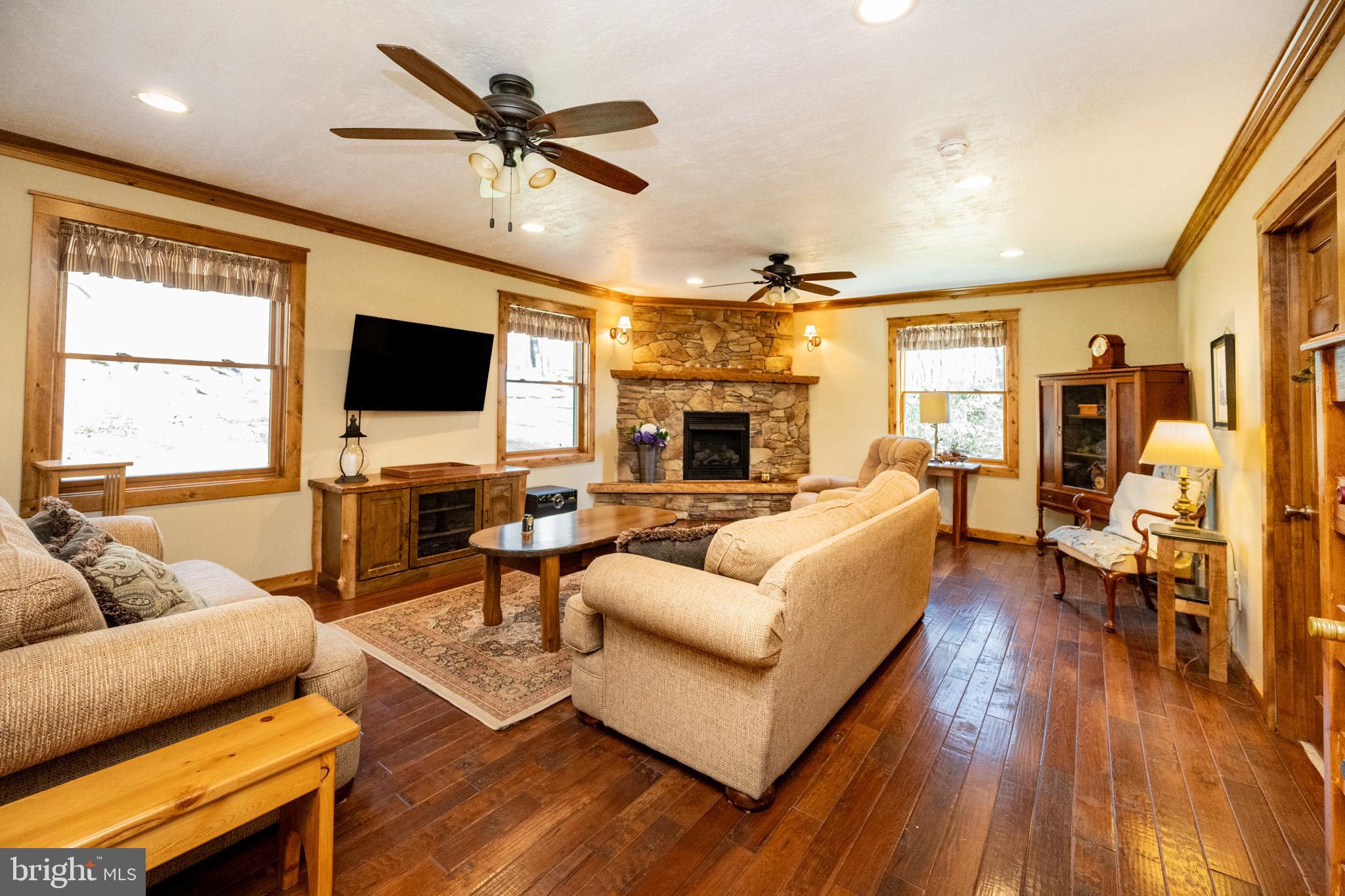 328 Stool Rock Road Oakland, MD 21550 - Photo 47 of 123 a living room with furniture a ceiling fan a fireplace and a flat screen tv
