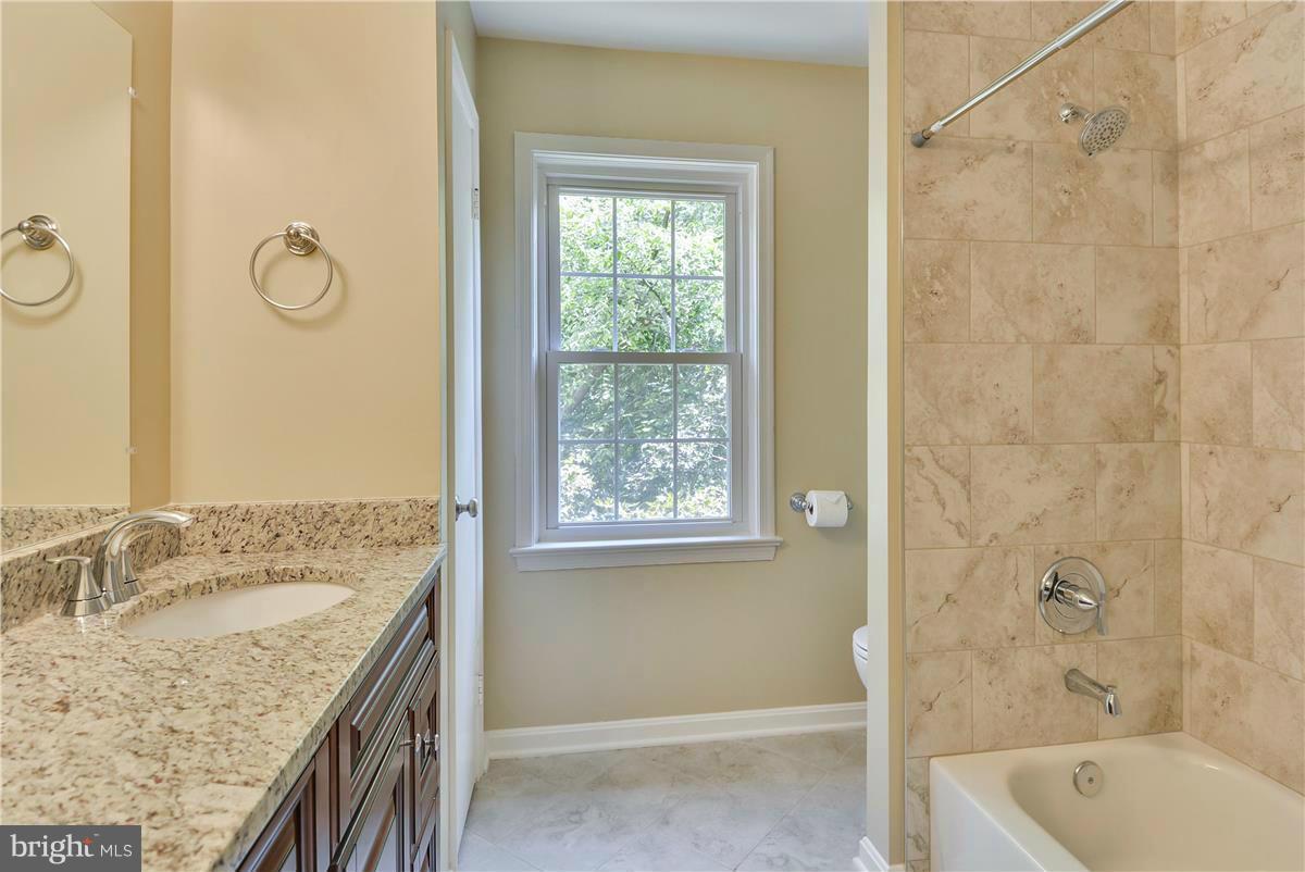 15212 Philip Lee Road Chantilly, VA 20151 - Photo 22 of 30 a bathroom with a granite countertop sink a mirror a bathtub and shower