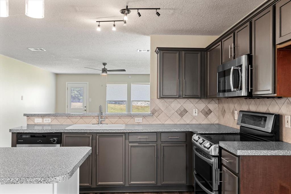 1448 Ridgecrest Drive Little Elm, TX 75068 - Photo 11 of 29 a kitchen with granite countertop a sink and stove
