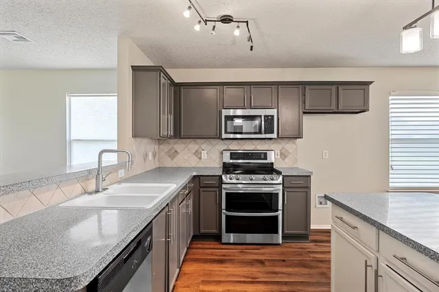 a kitchen with stainless steel appliances granite countertop a sink stove microwave and refrigerator