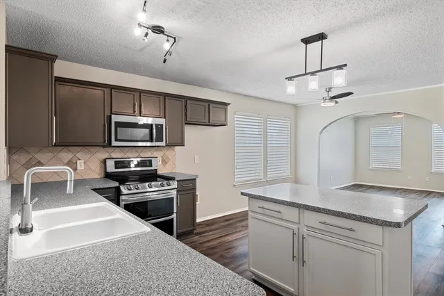 a kitchen with stainless steel appliances granite countertop a sink a stove top oven a counter space and cabinets