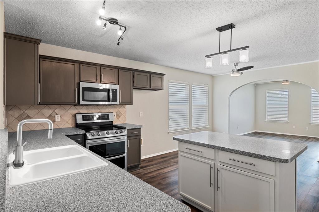 1448 Ridgecrest Drive Little Elm, TX 75068 - Photo 14 of 29 a kitchen with stainless steel appliances granite countertop a sink a stove top oven a counter space and cabinets