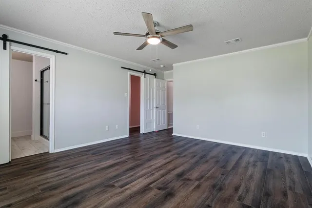 a view of an empty room with wooden floor and a ceiling fan