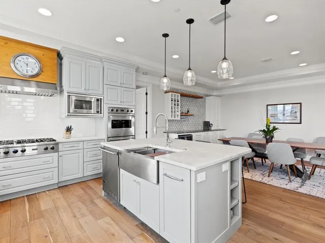 a kitchen with stainless steel appliances granite countertop a sink a stove a refrigerator and island with wooden floor