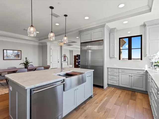 a kitchen with stainless steel appliances granite countertop a sink a stove a refrigerator and island with wooden floor