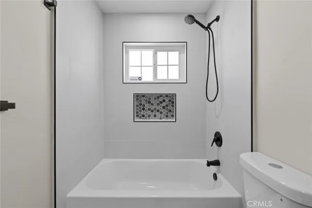 a bathroom with a granite countertop sink a toilet a mirror and shower