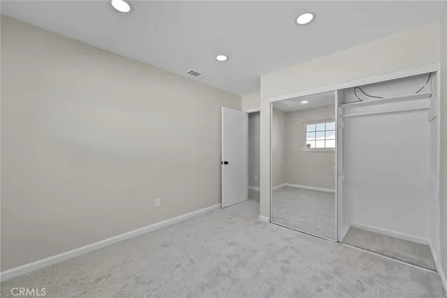 a view of an empty room with wooden floor and window
