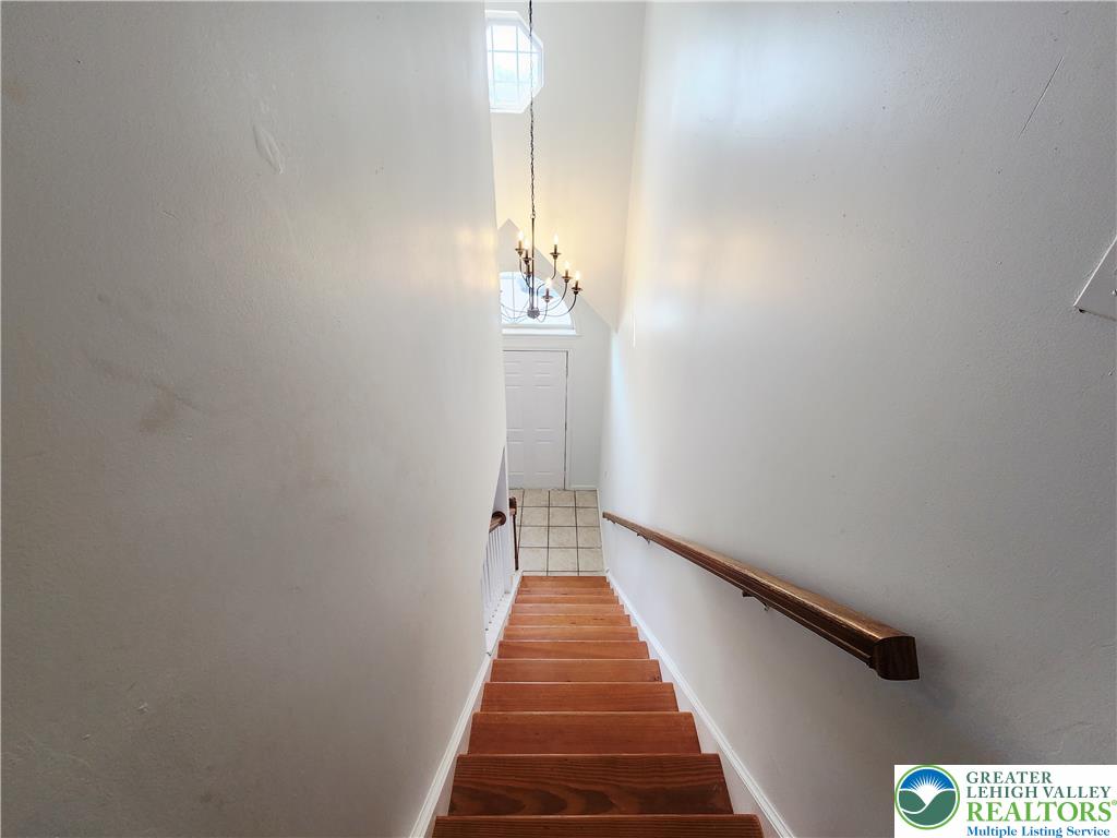237 Ridings Circle Macungie, PA 18062 - Photo 44 of 70 Rich wood stairs descend toward a tiled foyer under a high vaulted ceiling.