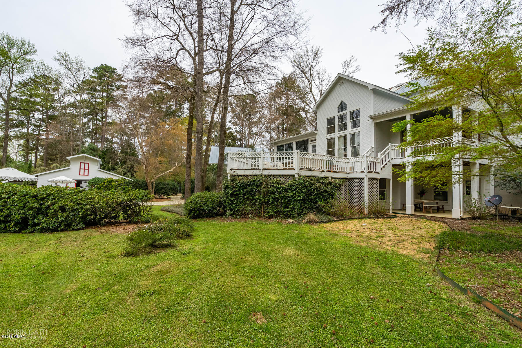 6150 Old Forsyth Road Macon, GA 31210 - Photo 21 of 50 a view of a white house next to a yard with plants and trees
