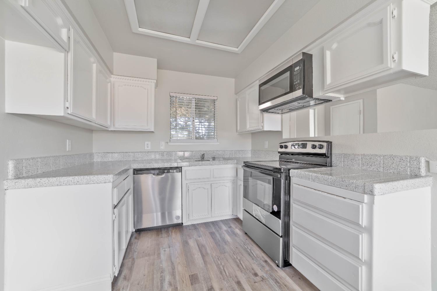 25612 Walden Avenue Madera, CA 93638 - Photo 19 of 33 a kitchen with stainless steel appliances granite countertop white cabinets stove a sink and dishwasher