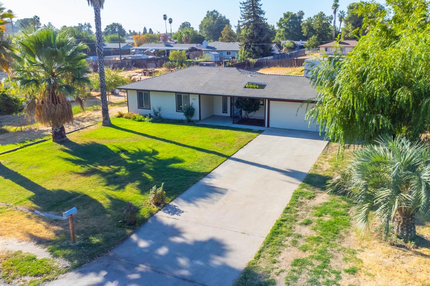 25612 Walden Avenue Madera, CA 93638 - Photo 2 of 33 a view of a white house with a swimming pool and lawn chairs under an umbrella