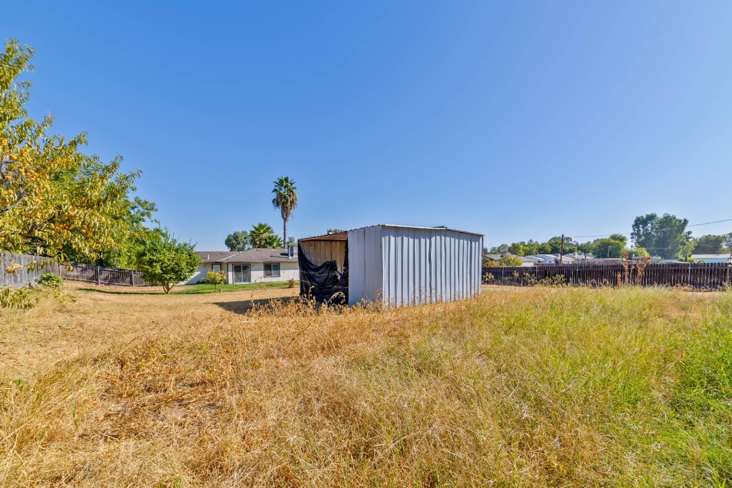25612 Walden Avenue Madera, CA 93638 - Photo 27 of 33 a backyard of a house with table and chairs under an umbrella