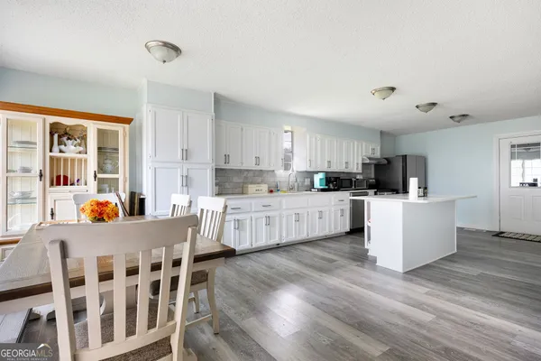 a kitchen with stainless steel appliances kitchen island wooden floors and white cabinets