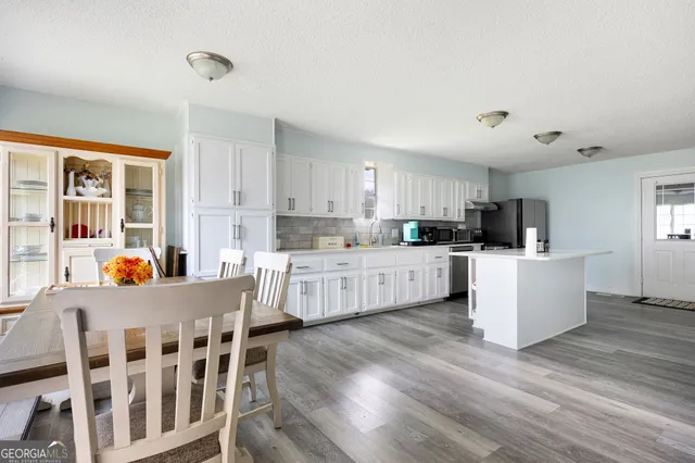 a kitchen with stainless steel appliances kitchen island wooden floors and white cabinets