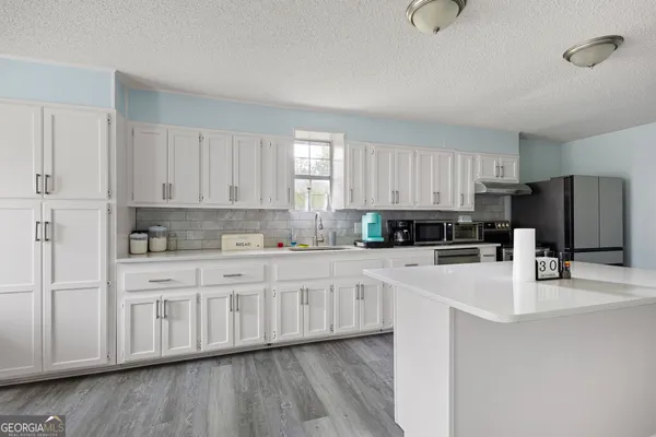 a kitchen with stainless steel appliances granite countertop a stove a sink and white cabinets