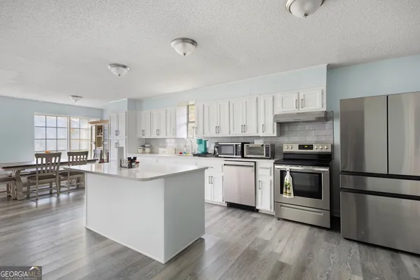 a kitchen with stainless steel appliances a sink a stove a refrigerator cabinets and wooden floor