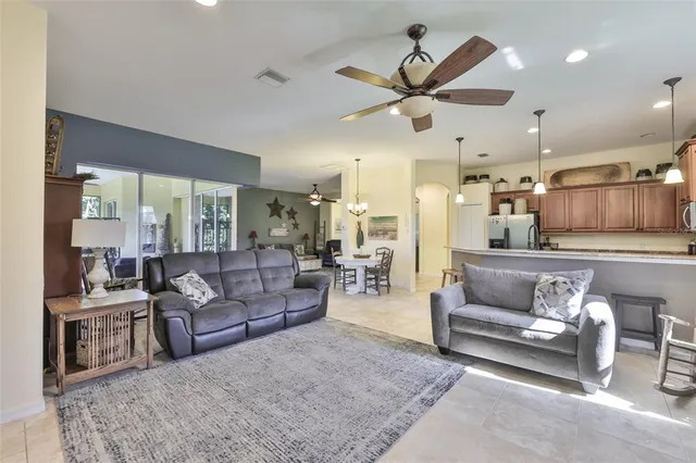 a living room with furniture kitchen view and a chandelier