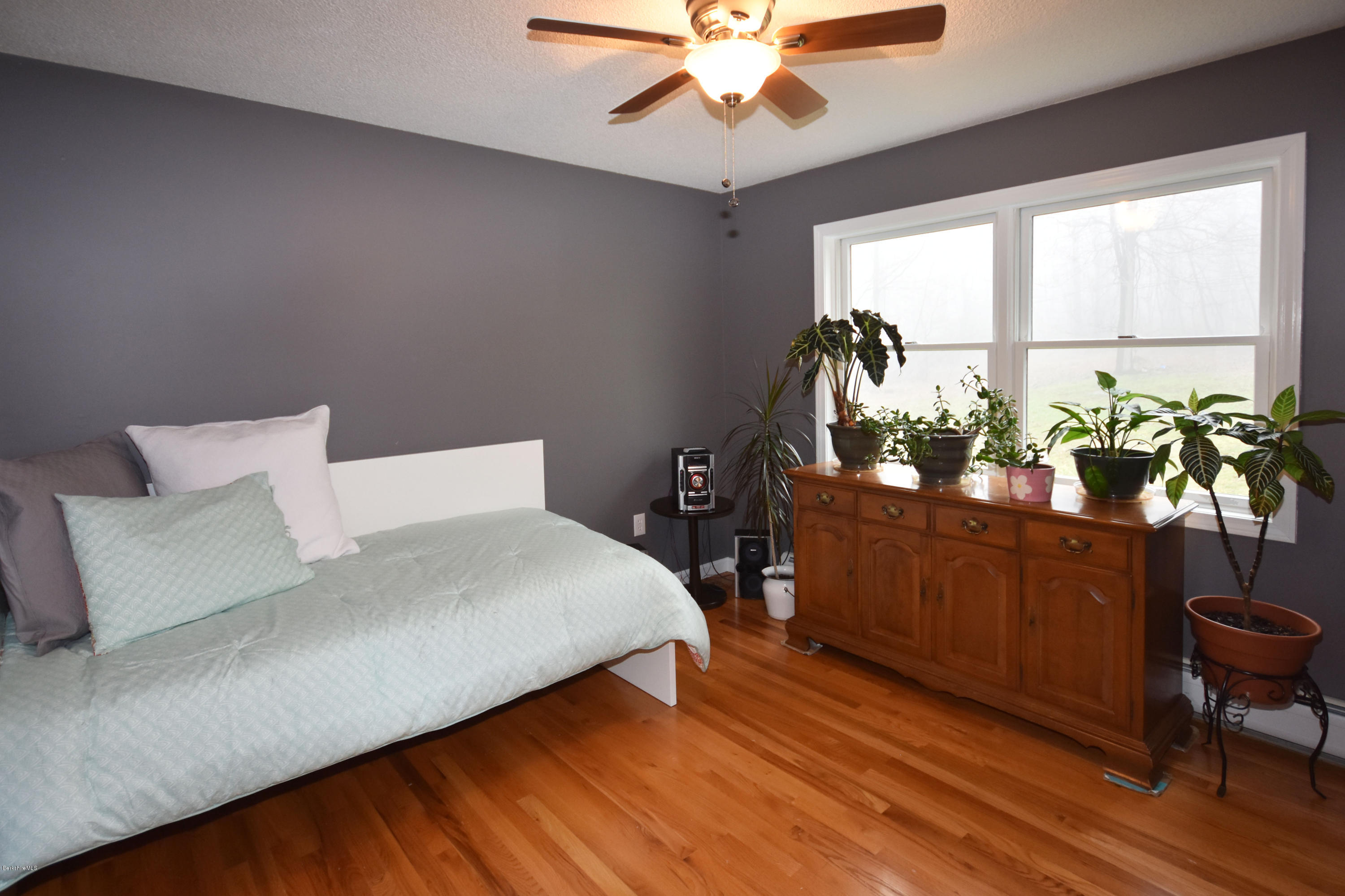1246 Jacobs Ladder Road Becket, MA 01223 - Photo 23 of 54 a bedroom with a bed table closet with a potted plant on the dresser and a large window