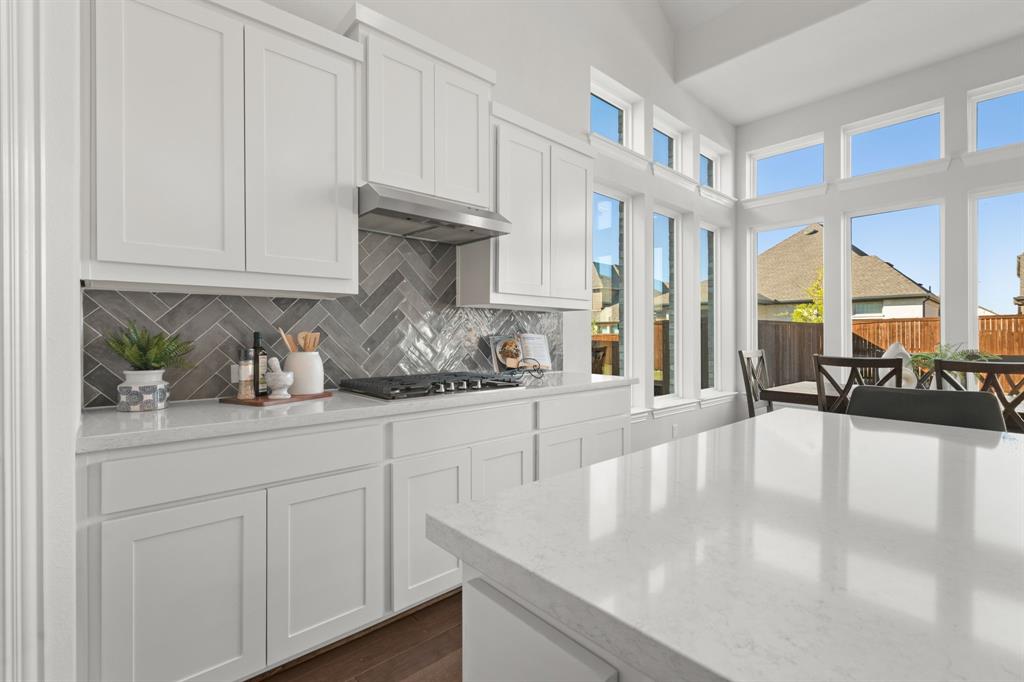 1320 Cartona Road Fate, TX 75087 - Photo 18 of 35 White shaker cabinetry with a herringbone tile backsplash and quartz island