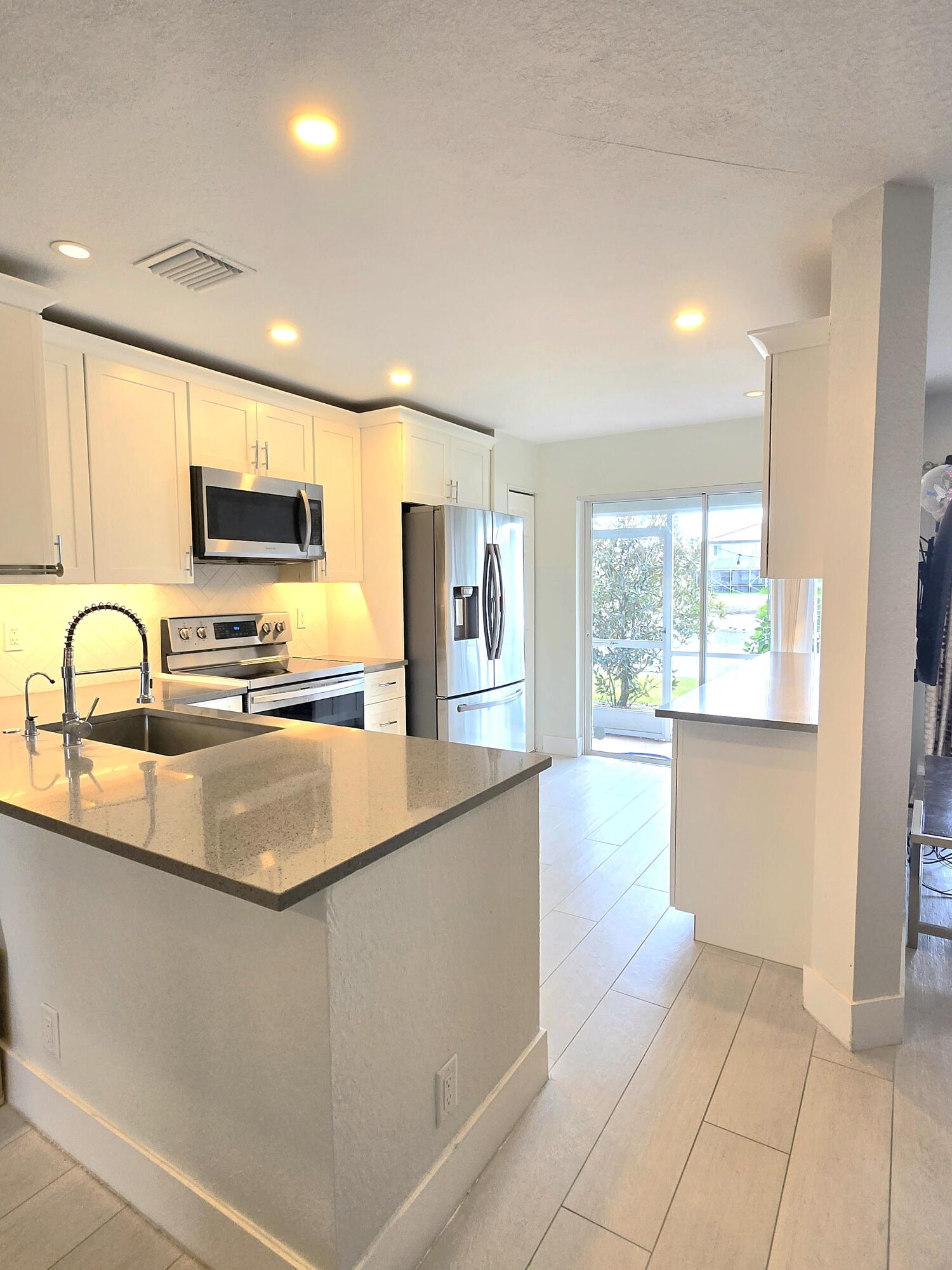 8018 Big Pine Way Riviera Beach, FL 33407 - Photo 3 of 9 a kitchen with stainless steel appliances granite countertop a sink a stove and cabinets