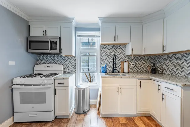 a kitchen with white cabinets sink and stainless steel appliances