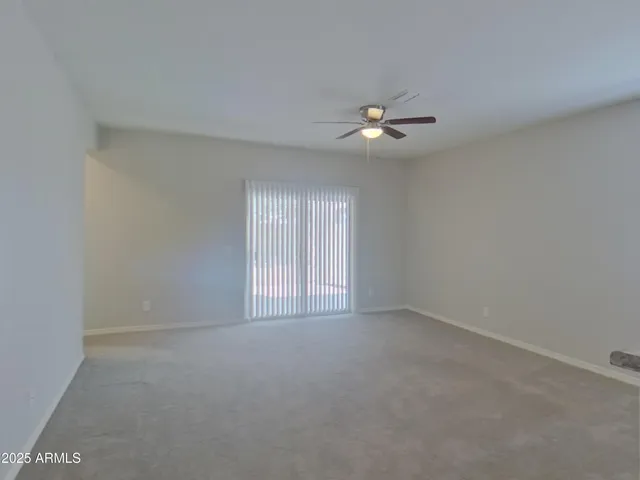 an empty room with chandelier fan and windows
