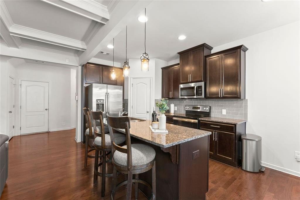 5713 Radford Loop Fairburn, GA 30213 - Photo 12 of 43 a kitchen with stainless steel appliances granite countertop wooden floor a dining table and chairs