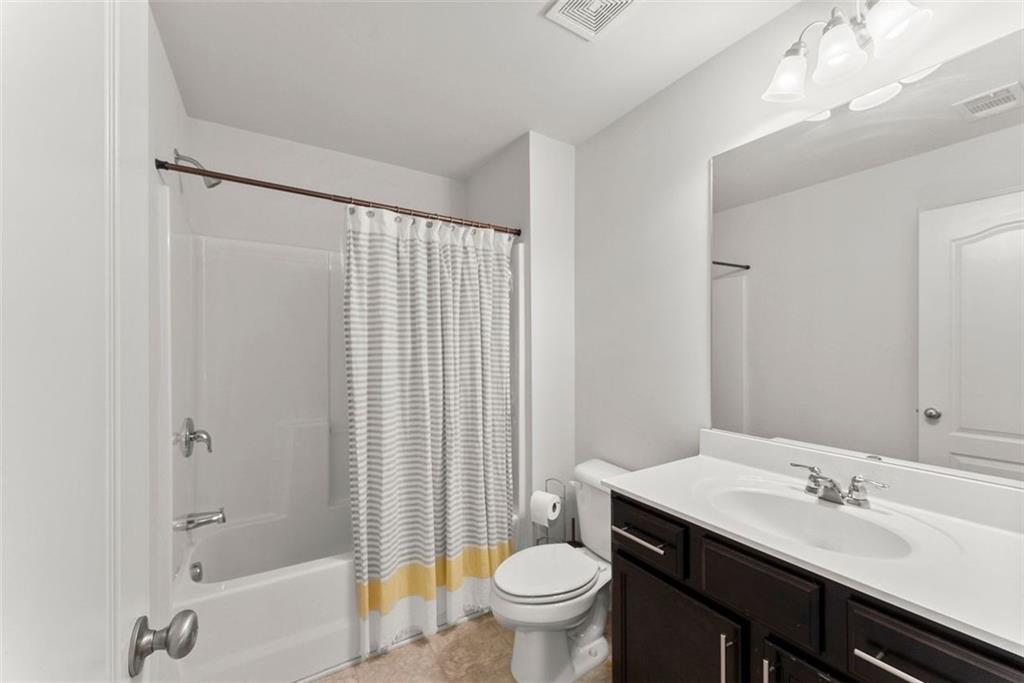 5713 Radford Loop Fairburn, GA 30213 - Photo 31 of 43 a bathroom with a granite countertop sink toilet a large mirror and shower