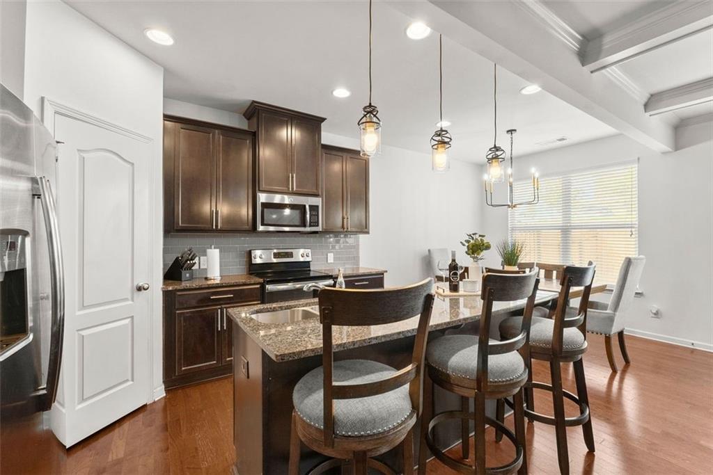 5713 Radford Loop Fairburn, GA 30213 - Photo 7 of 43 a kitchen with granite countertop a dining table chairs refrigerator and microwave