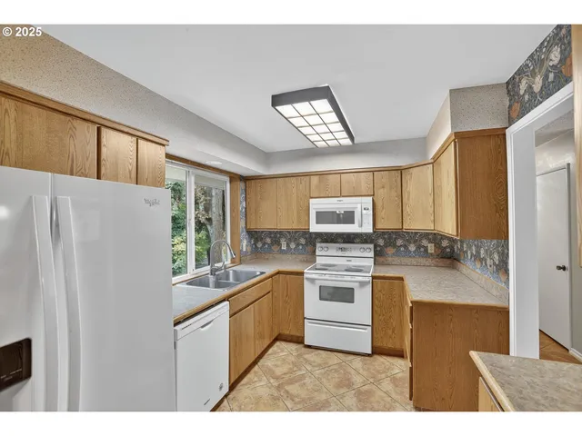 a kitchen with stainless steel appliances granite countertop a refrigerator a sink dishwasher a stove with white cabinets and wooden floor