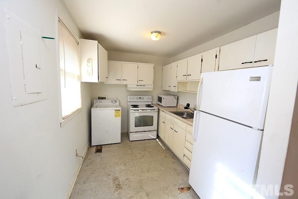 848 Newcombe Road Raleigh, NC 27610 - Photo 5 of 14 a kitchen with a refrigerator a stove top oven and white cabinets