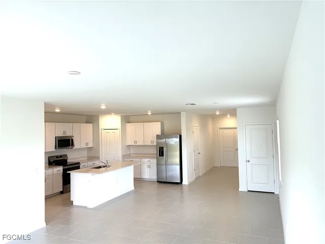 a view of kitchen with kitchen island white cabinets and refrigerator