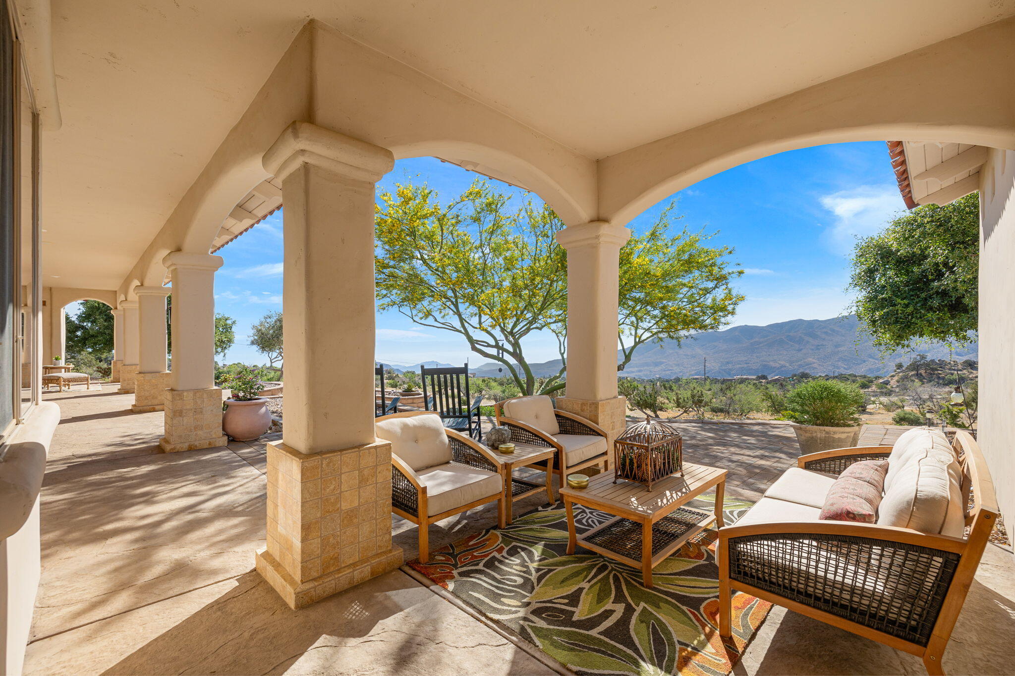 a view of a patio with couches and table and chairs with wooden floor and fence