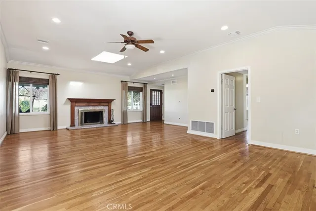 an empty room with wooden floor fireplace and windows