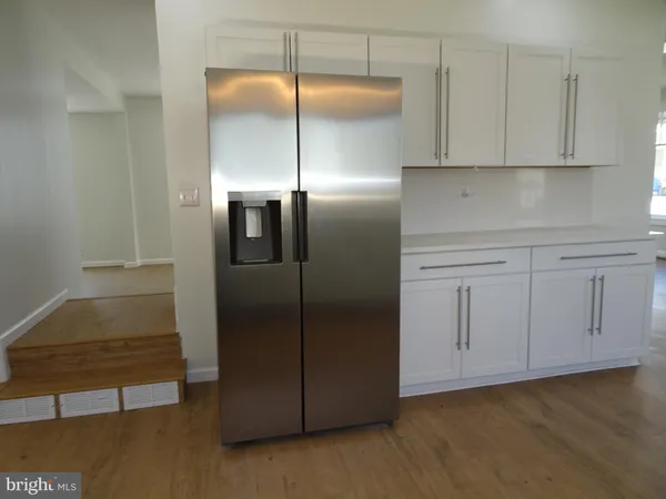 a view of kitchen with stainless steel appliances wooden floor and cabinets
