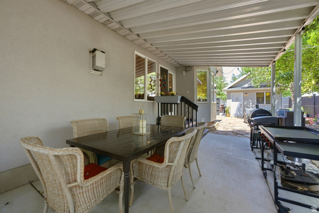 5196 Rodeo Circle Oakley, UT 84055 - Photo 42 of 57 Covered concrete patio featuring a textured stucco exterior, multiple large windows, and an outdoor wall-mounted light fixture