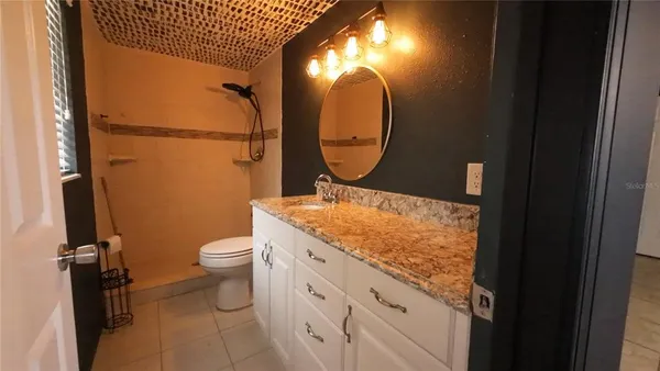 a bathroom with a granite countertop toilet sink and mirror