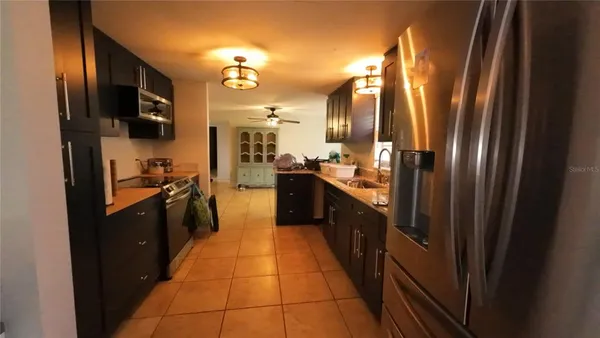 a kitchen with stainless steel appliances granite countertop a refrigerator a stove top oven and sink