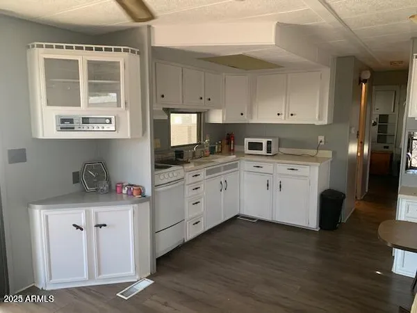 a kitchen with stainless steel appliances granite countertop a stove a sink dishwasher and white cabinets with wooden floor