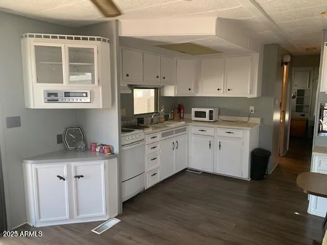 a kitchen with stainless steel appliances granite countertop a stove a sink dishwasher and white cabinets with wooden floor