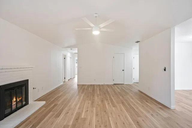 a view of empty room with wooden floor and fireplace